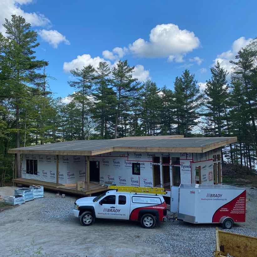The branded BRADY truck and enclosed trailer parked at a new home under construction.