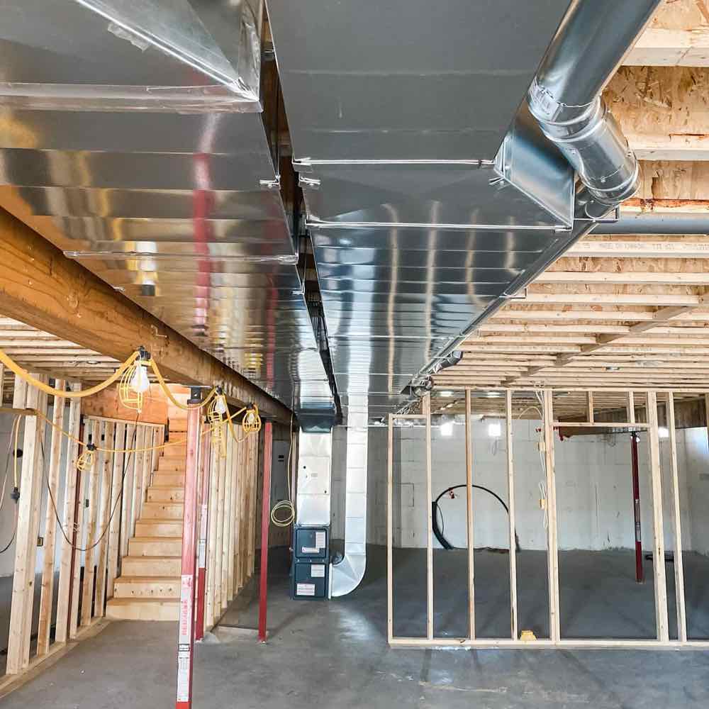 Gleaming custom sheet-metal trunk ductwork and a new furnace, fabricated and installed by BRADY in a basement.